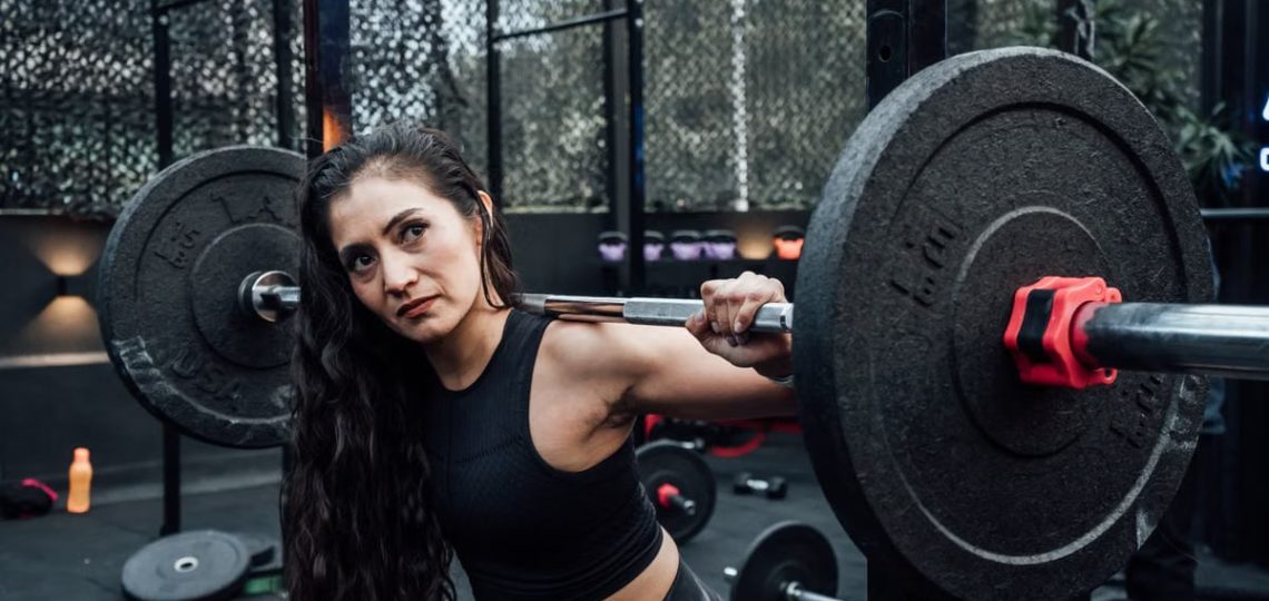 A determined woman lifting weights in a modern gym, embodying fitness and strength.